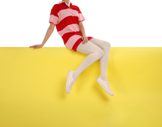 Woman wearing white tights and stylish shoes sitting on color background, closeup