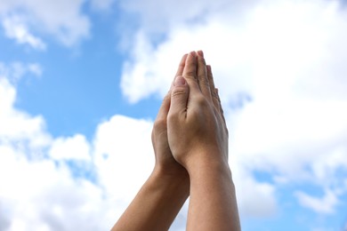Photo of Woman with clasped hands praying against blue sky, closeup