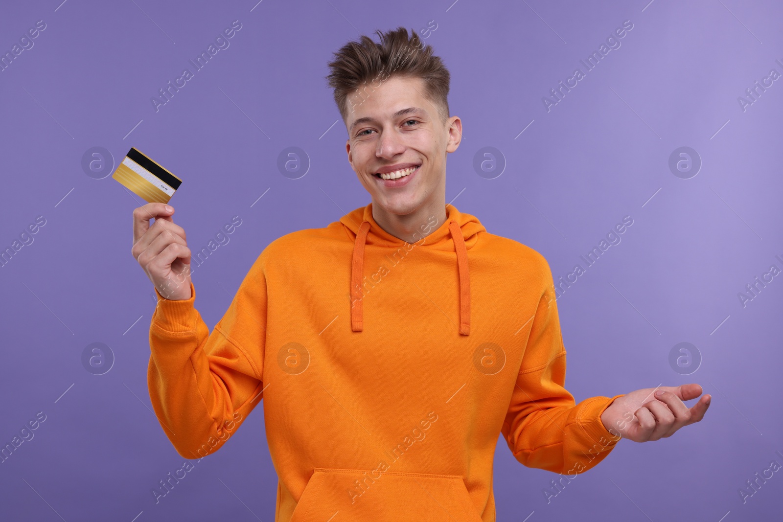 Photo of Happy man with credit card on purple background