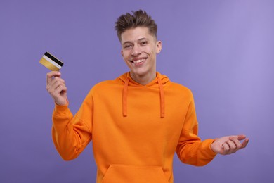 Photo of Happy man with credit card on purple background