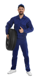 Full length portrait of professional auto mechanic with wheel on white background