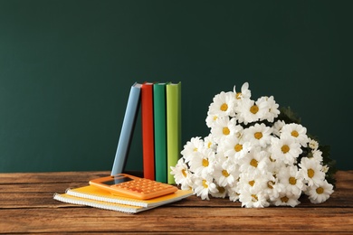 Photo of Set of stationery and flowers on wooden table near chalkboard. Teacher's Day