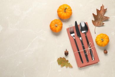 Photo of Cutlery, napkin and autumn decoration on beige marble background, flat lay with space for text. Table setting