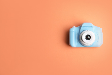 Photo of Light blue toy camera on orange background, top view with space for text. Future photographer