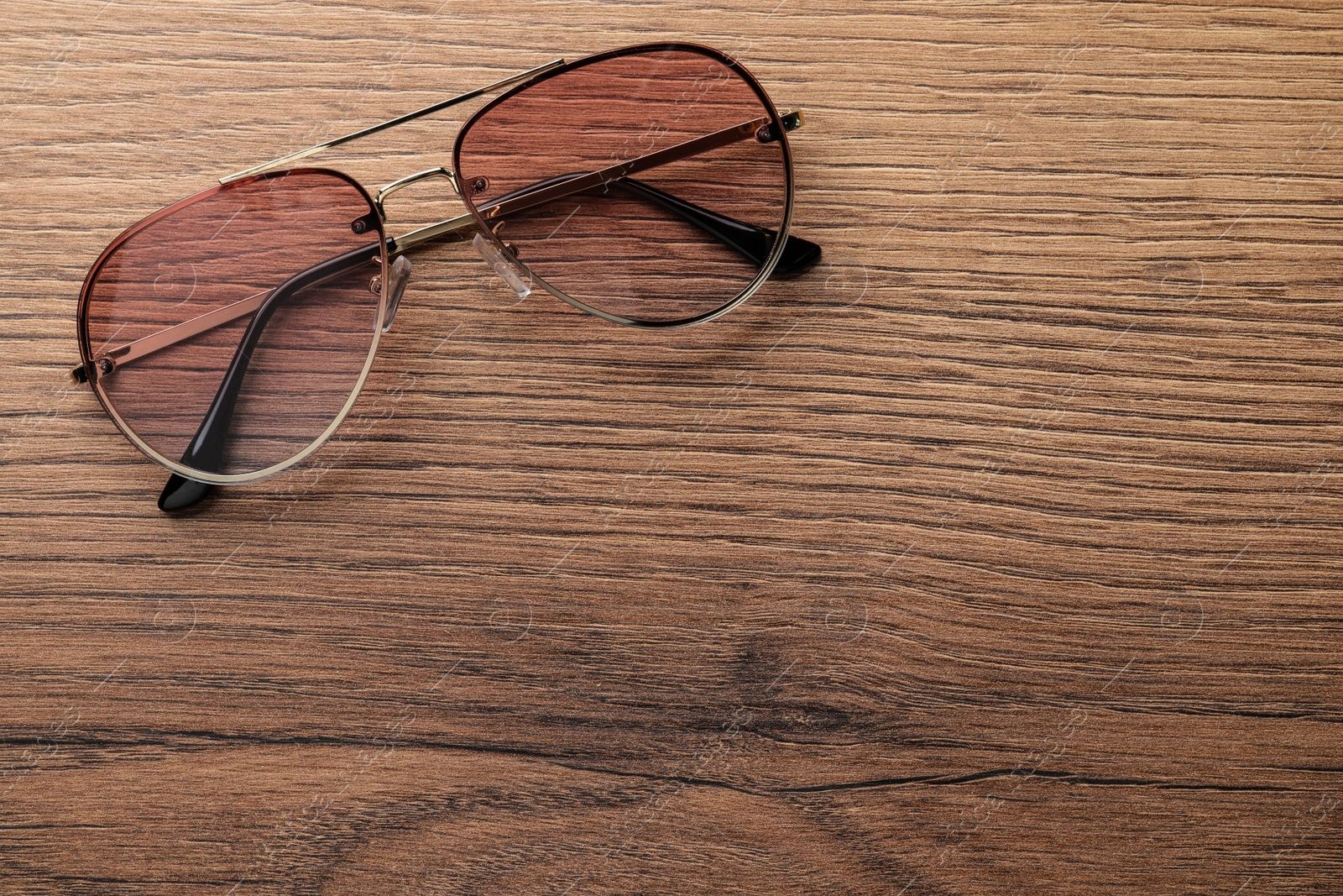 Photo of New stylish sunglasses on wooden table, top view. Space for text