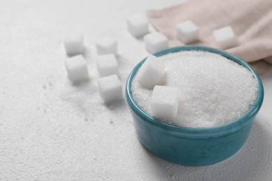 Photo of Different types of sugar in bowl on white table, closeup. Space for text