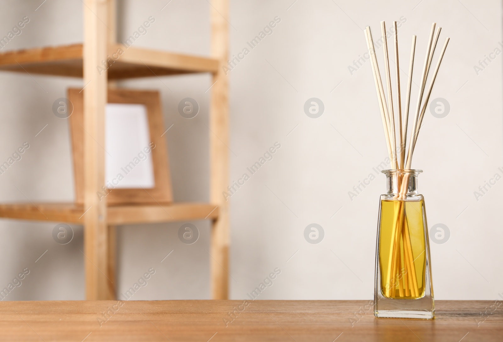 Photo of Reed air freshener on wooden table indoors, space for text