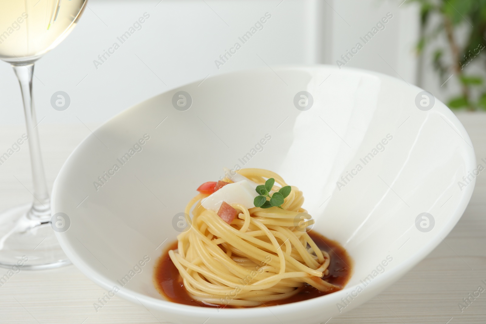 Photo of Tasty spaghetti with sauce served on white wooden table, closeup. Exquisite presentation of pasta dish