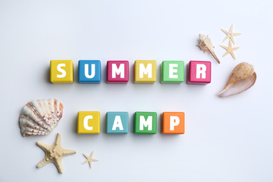 Colorful wooden cubes with phrase SUMMER CAMP on white background, flat lay