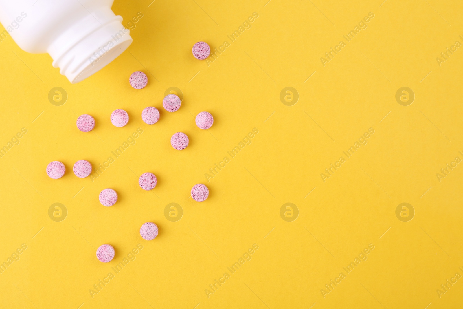 Photo of Bottle and vitamin pills on yellow background, top view. Space for text