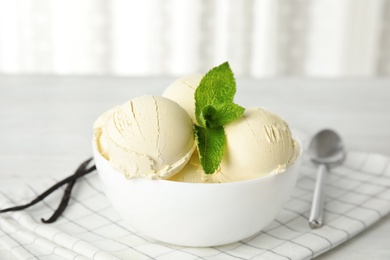 Photo of Delicious vanilla ice cream with mint in bowl served on table