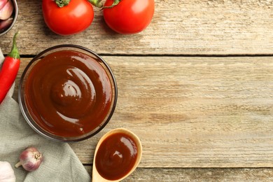 Flat lay composition with tasty barbeque sauce in bowl on wooden table. Space for text