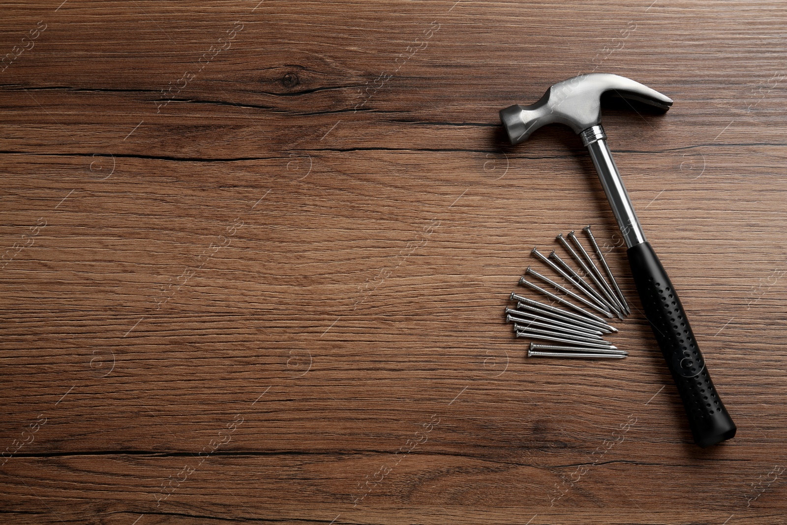 Photo of Hammer and metal nails on wooden table, flat lay. Space for text