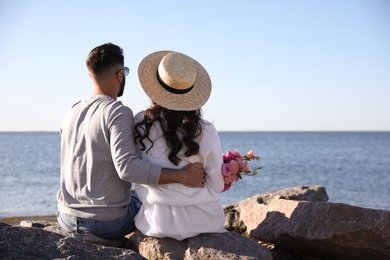 Young couple with flowers at beach. Honeymoon trip