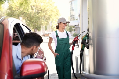 Young worker refueling car at modern gas station