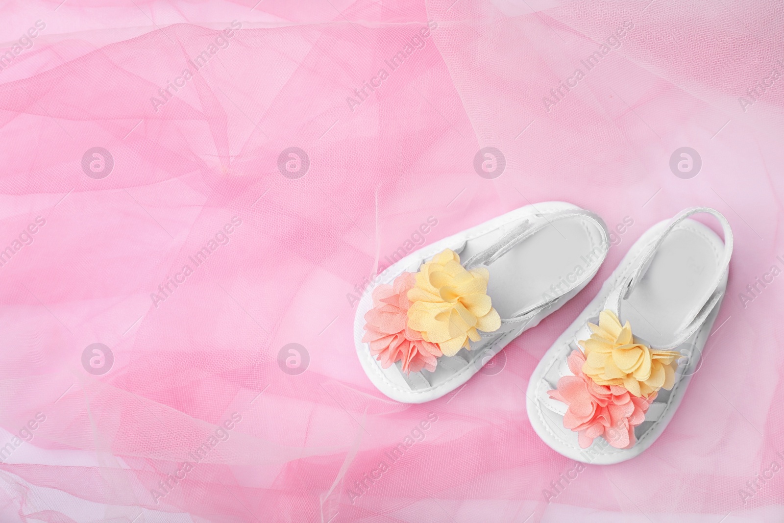 Photo of Pair of cute baby sandals on color fabric, top view