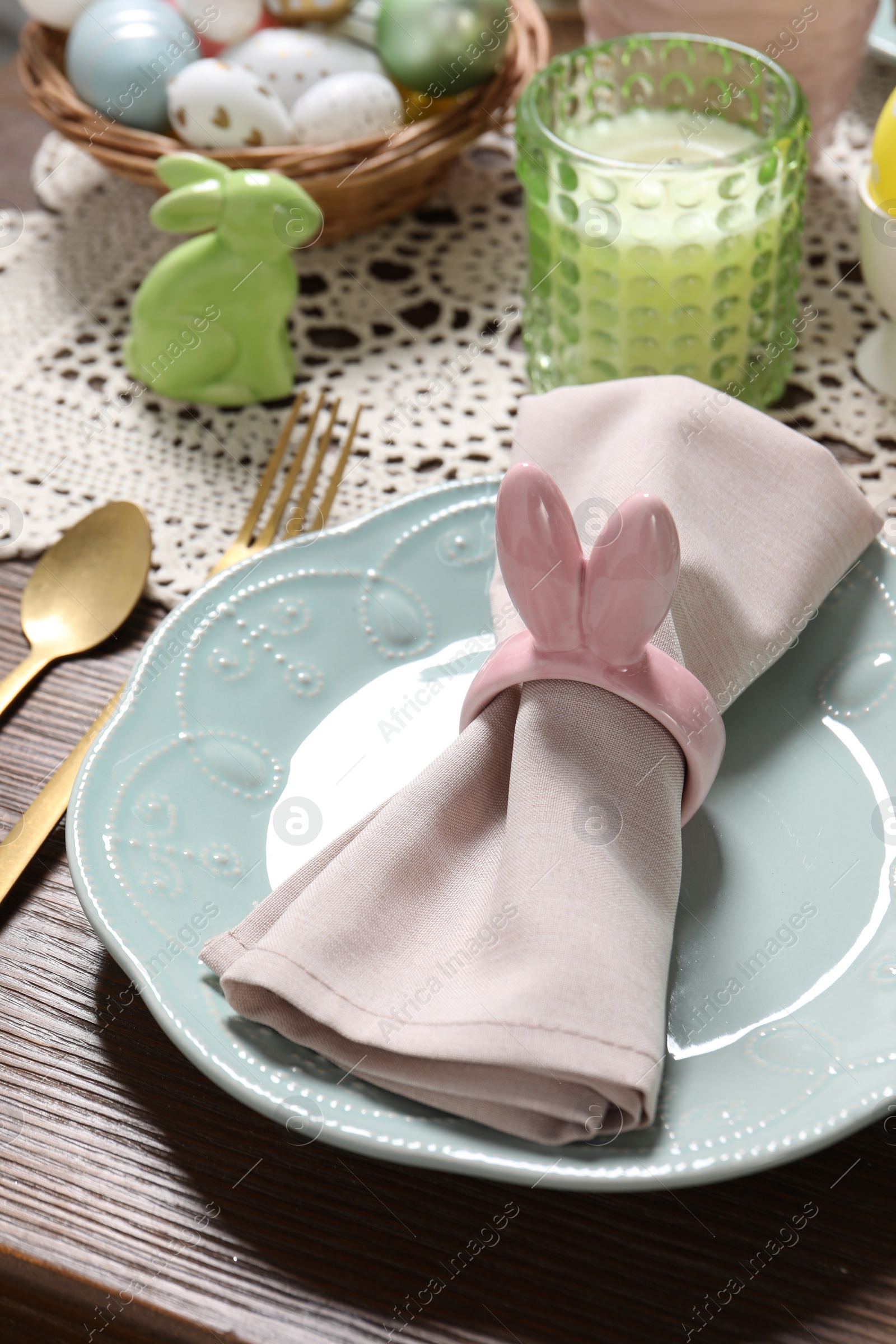 Photo of Festive table setting with napkin ring in shape of bunny ears, closeup. Easter celebration