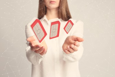 Image of Woman demonstrating SIM cards of different sizes on light background, closeup 