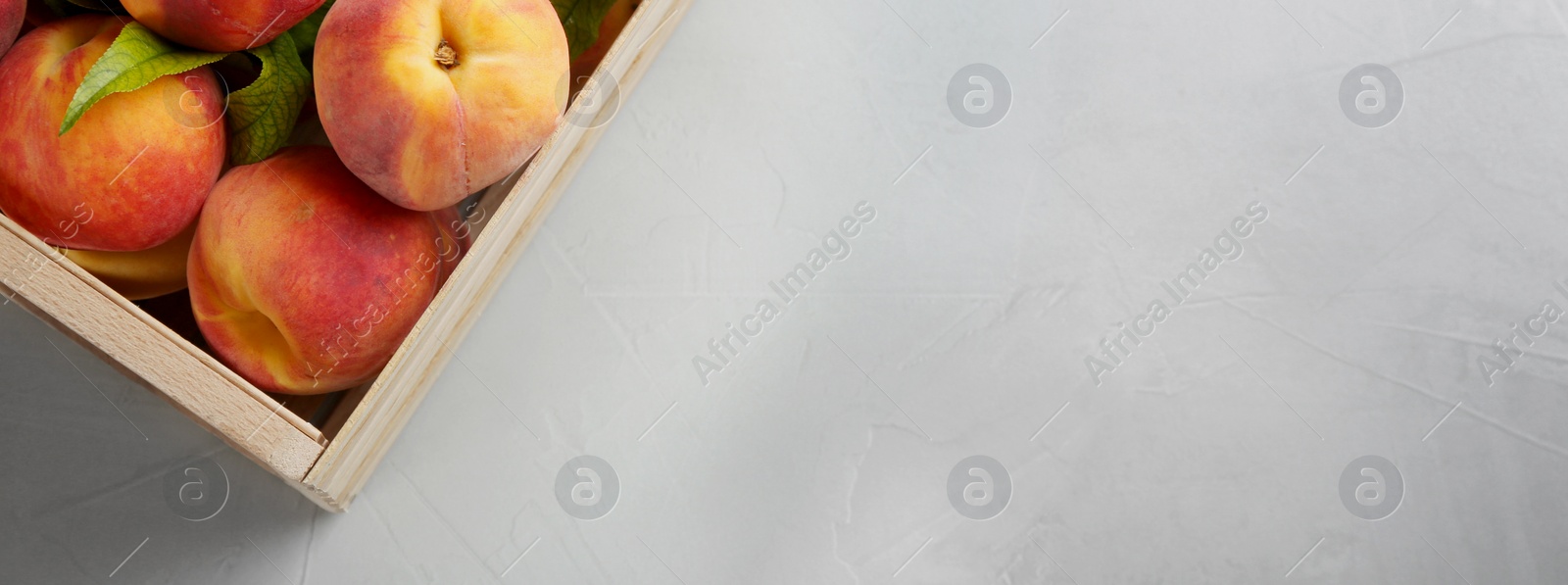 Image of Fresh ripe peaches in crate on light grey background, top view. Banner design with space for text