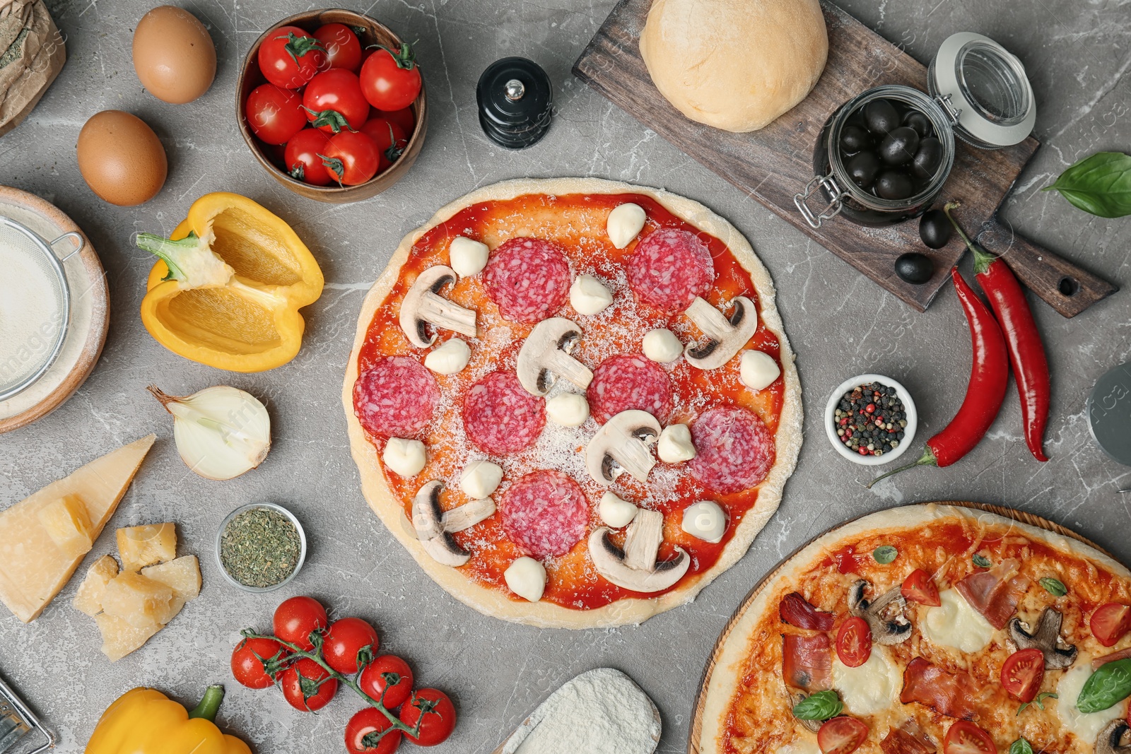 Photo of Composition with unbaked pizza and ingredients on table, top view