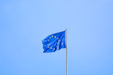 Flag of European Union fluttering on pole outdoors, space for text