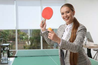 Photo of Business woman with tennis racket and ball near ping pong table in office. Space for text