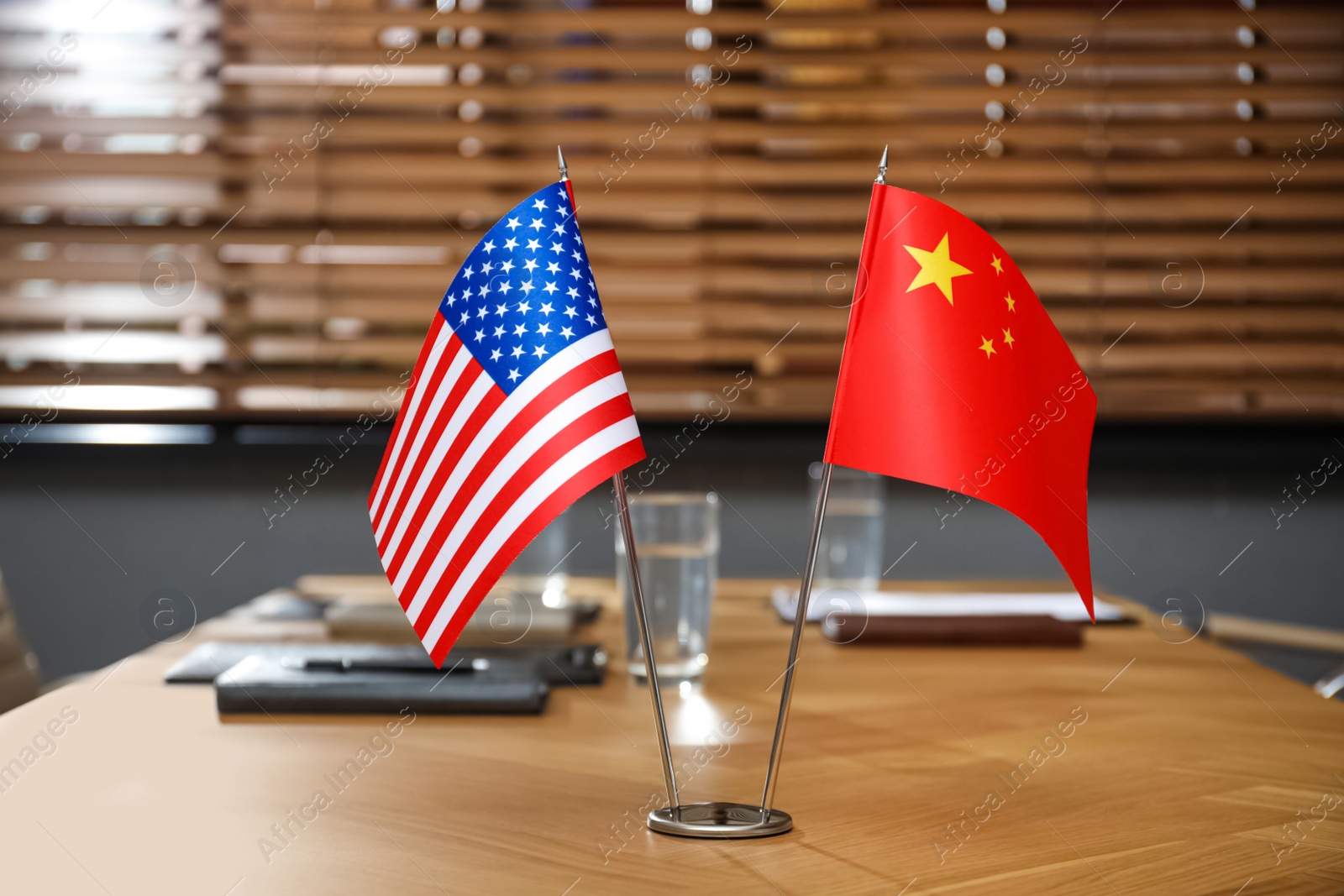 Photo of USA and China flags on wooden table in office. International relations