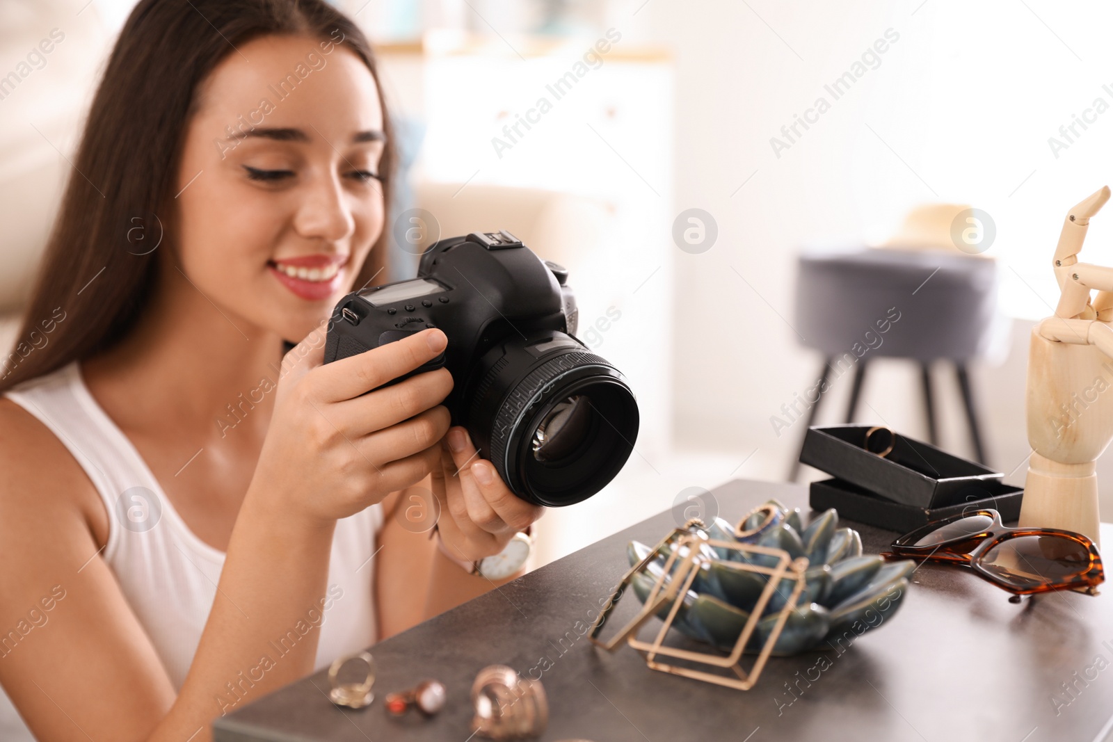 Photo of Young photographer taking picture of jewelry indoors, closeup