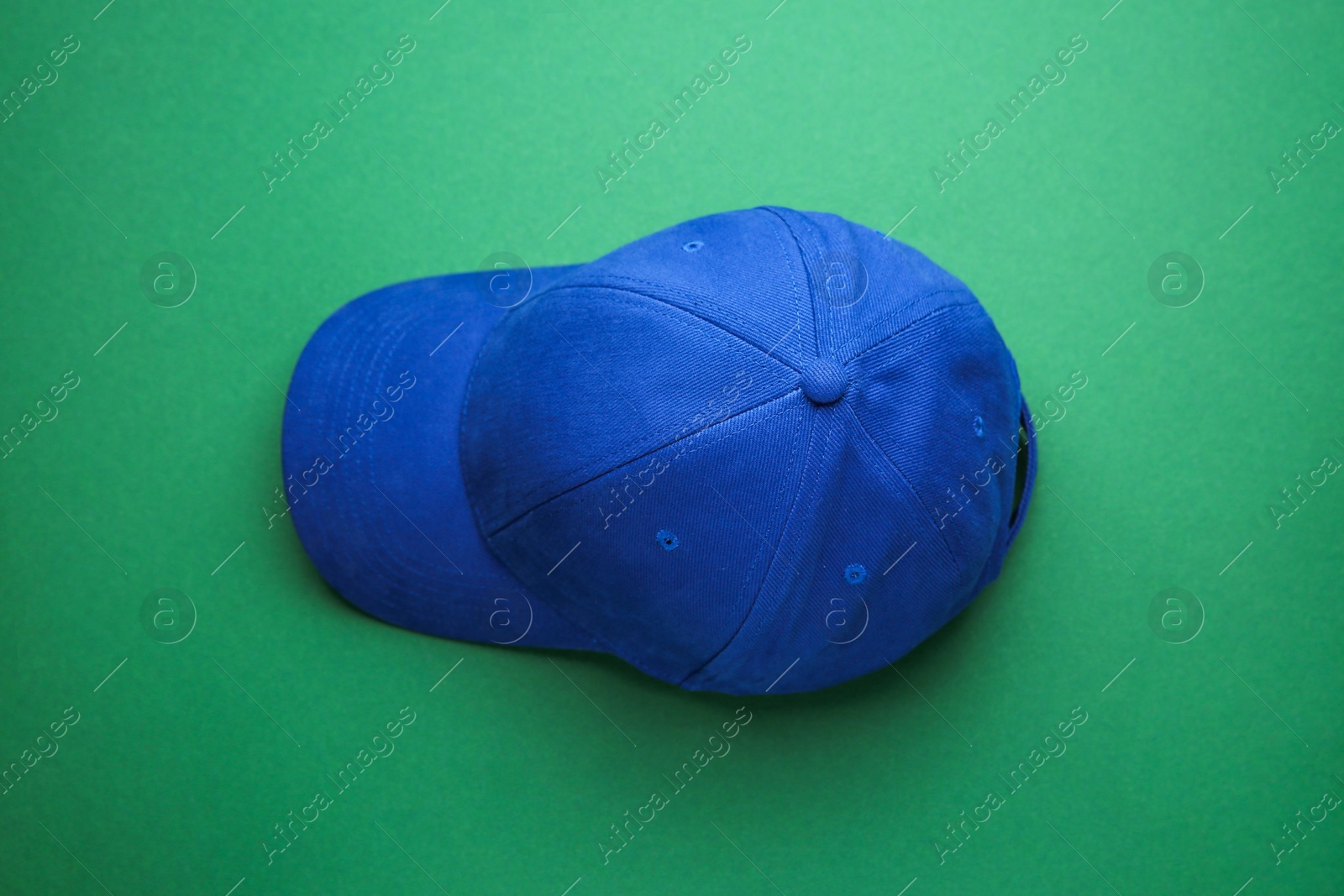 Photo of Stylish blue baseball cap on green background, top view