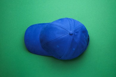 Stylish blue baseball cap on green background, top view