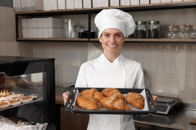 Professional baker with freshly baked croissants in store