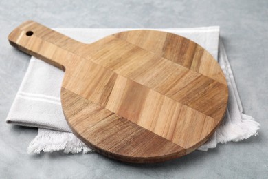Photo of One wooden cutting board on light grey table. Cooking utensil