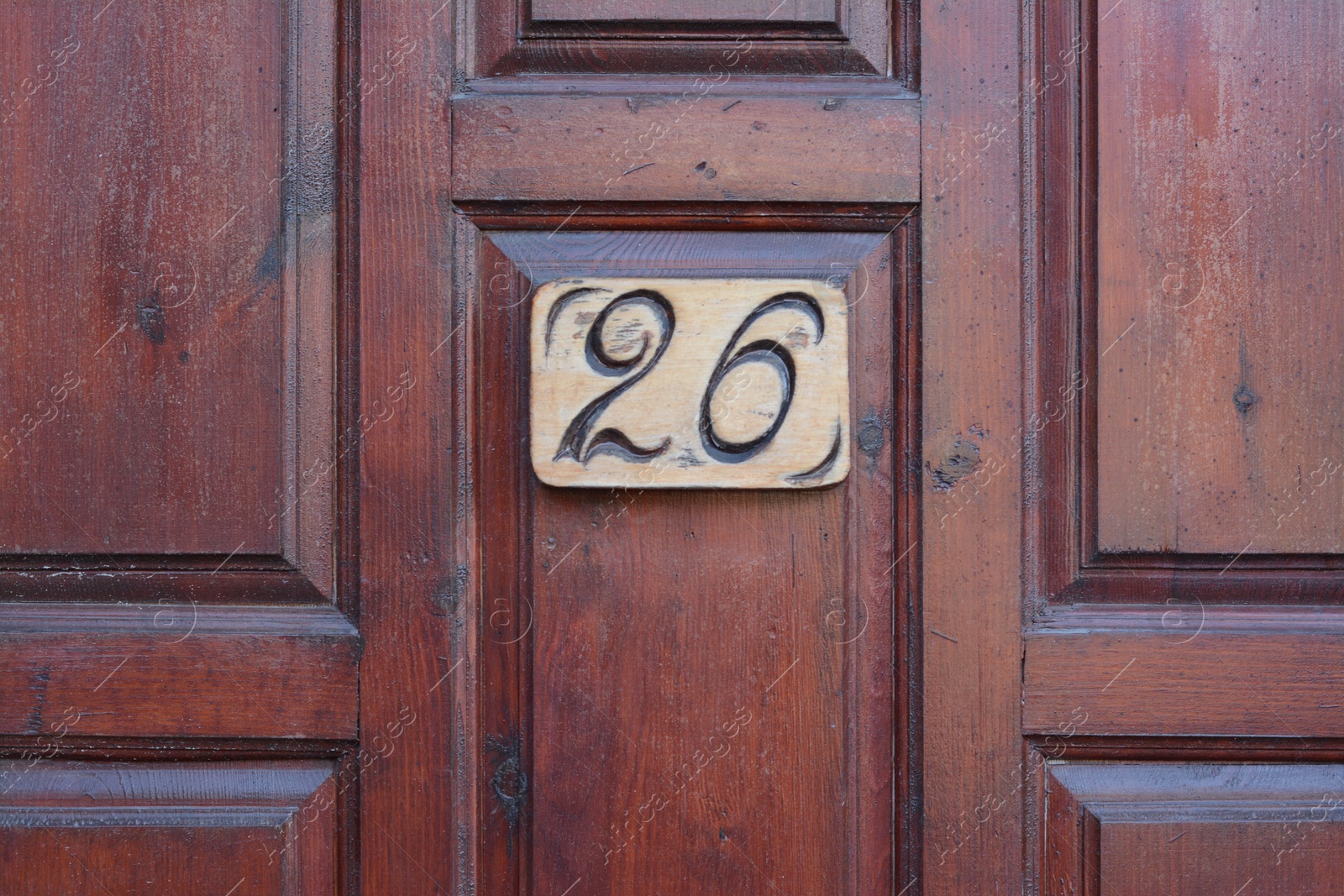 Photo of Plate with house number twenty six on wooden door, closeup