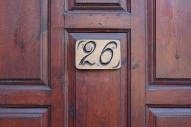Plate with house number twenty six on wooden door, closeup