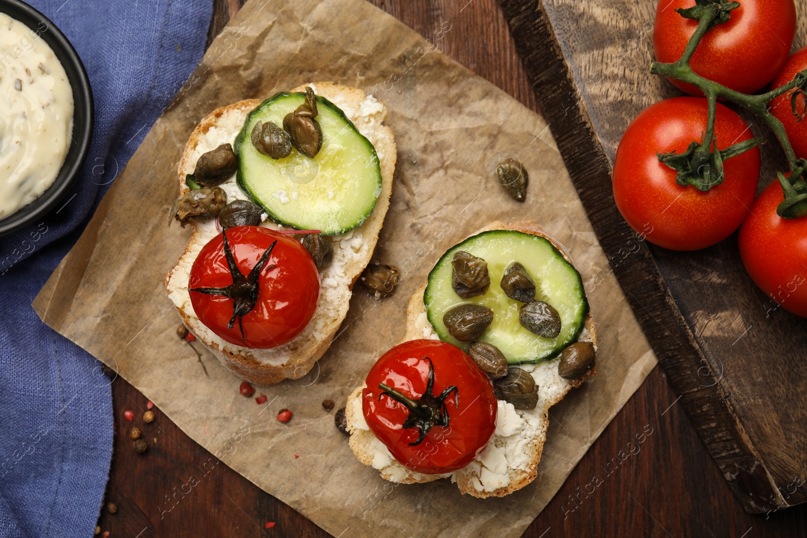 Photo of Tasty bruschettas with vegetables and capers on wooden table, flat lay