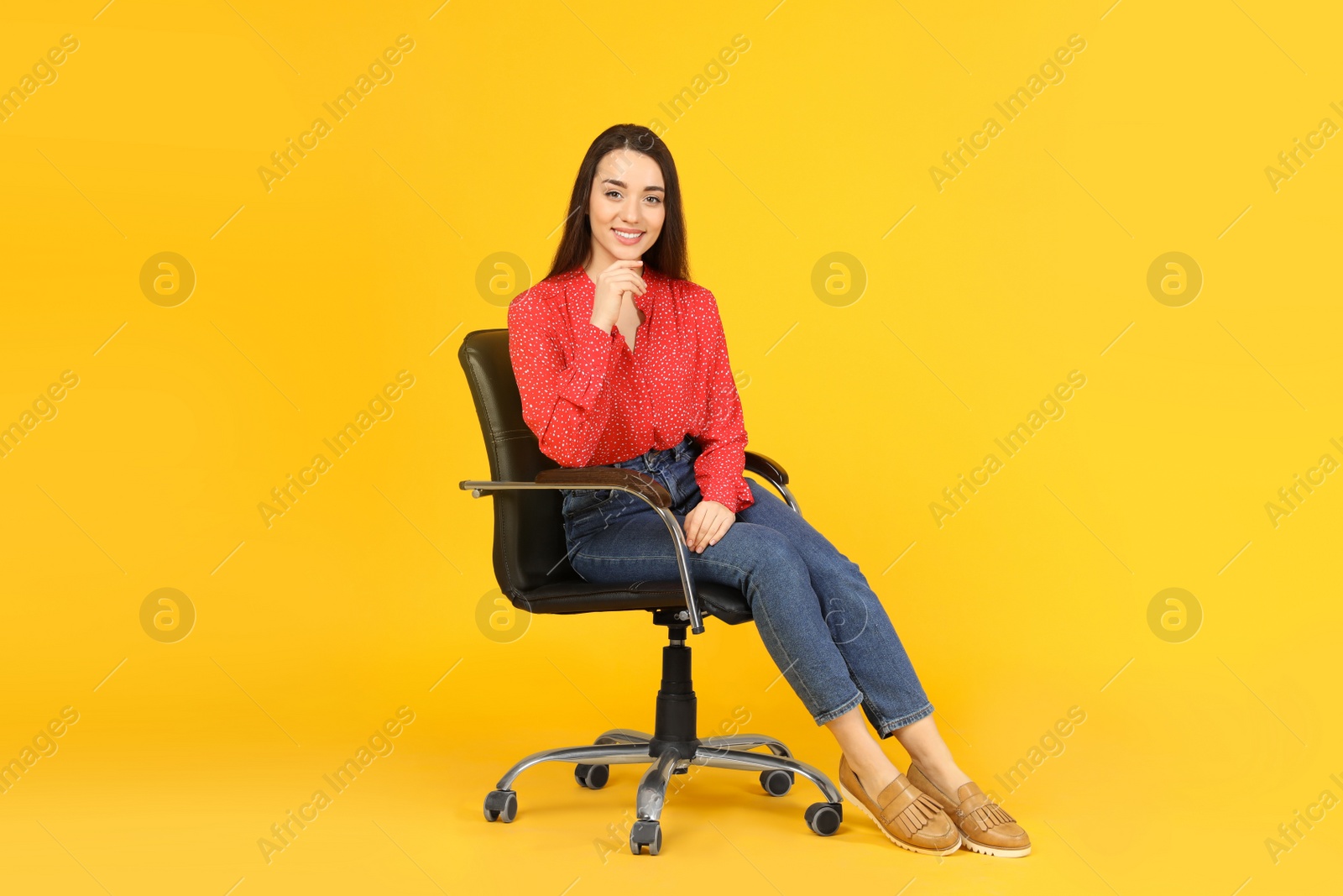 Photo of Young woman sitting in comfortable office chair on yellow background