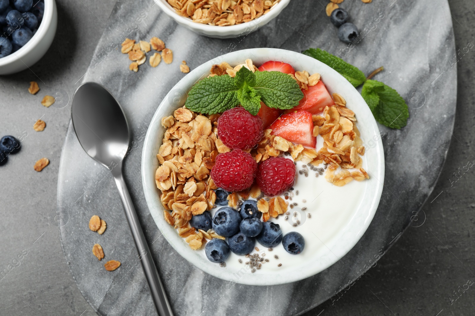 Photo of Tasty homemade granola with yogurt and berries on grey table, flat lay. Healthy breakfast