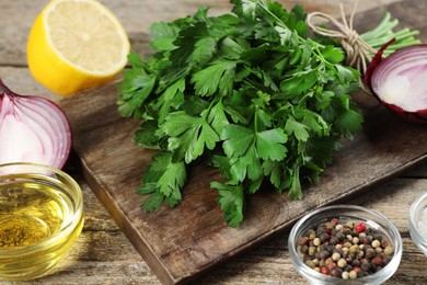 Board with fresh parsley, spices and other products on wooden table, closeup
