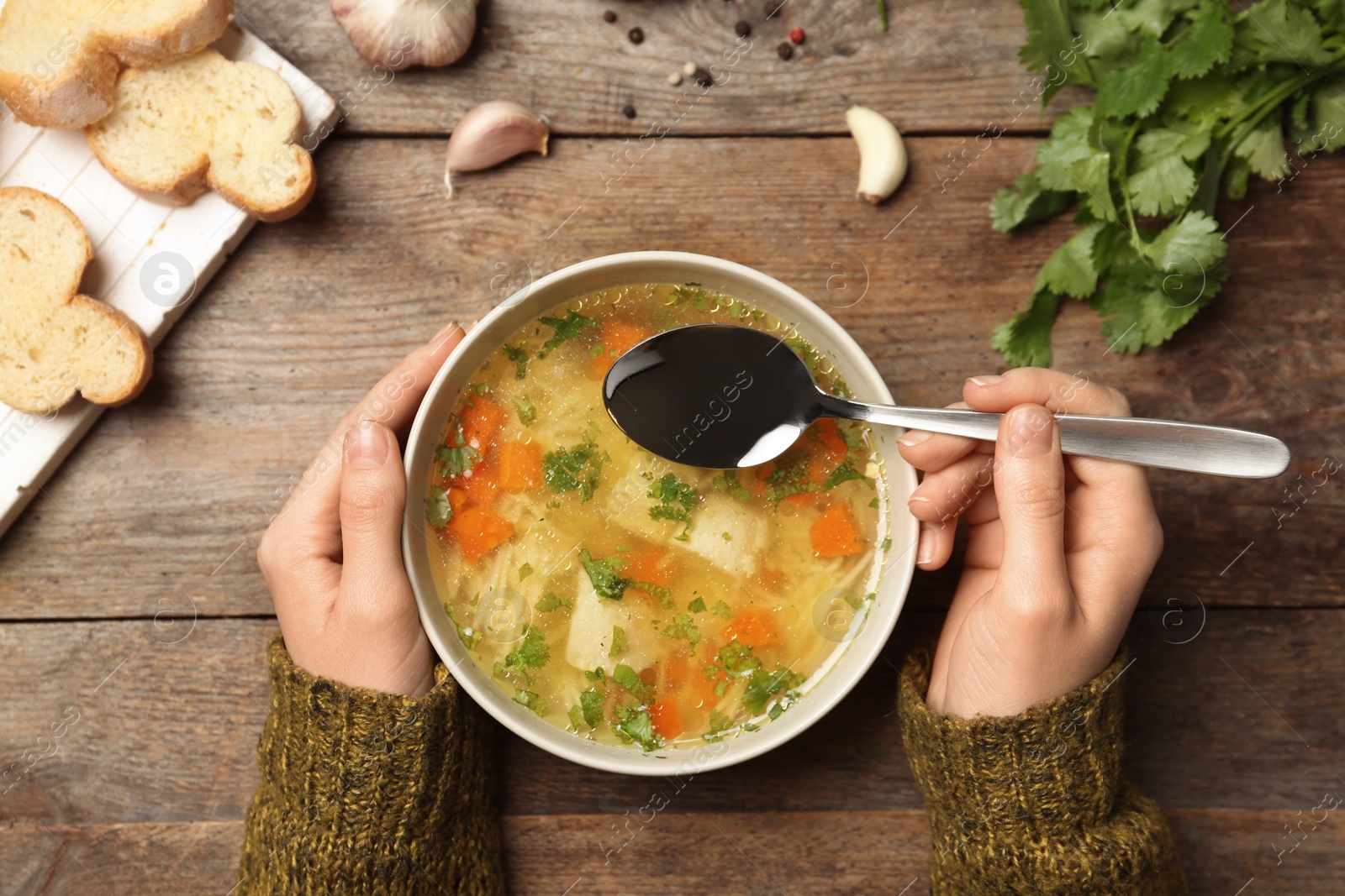 Photo of Woman eating fresh homemade chicken soup at table, top view