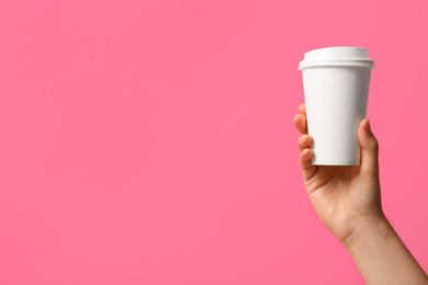 Photo of Woman holding takeaway paper coffee cup on pink background, closeup. Space for text