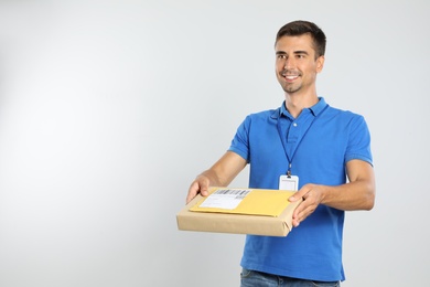 Happy young courier with parcel and envelope on white background. Space for text