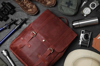 Photo of Flat lay composition with leather backpack and camping equipment for tourism on black background