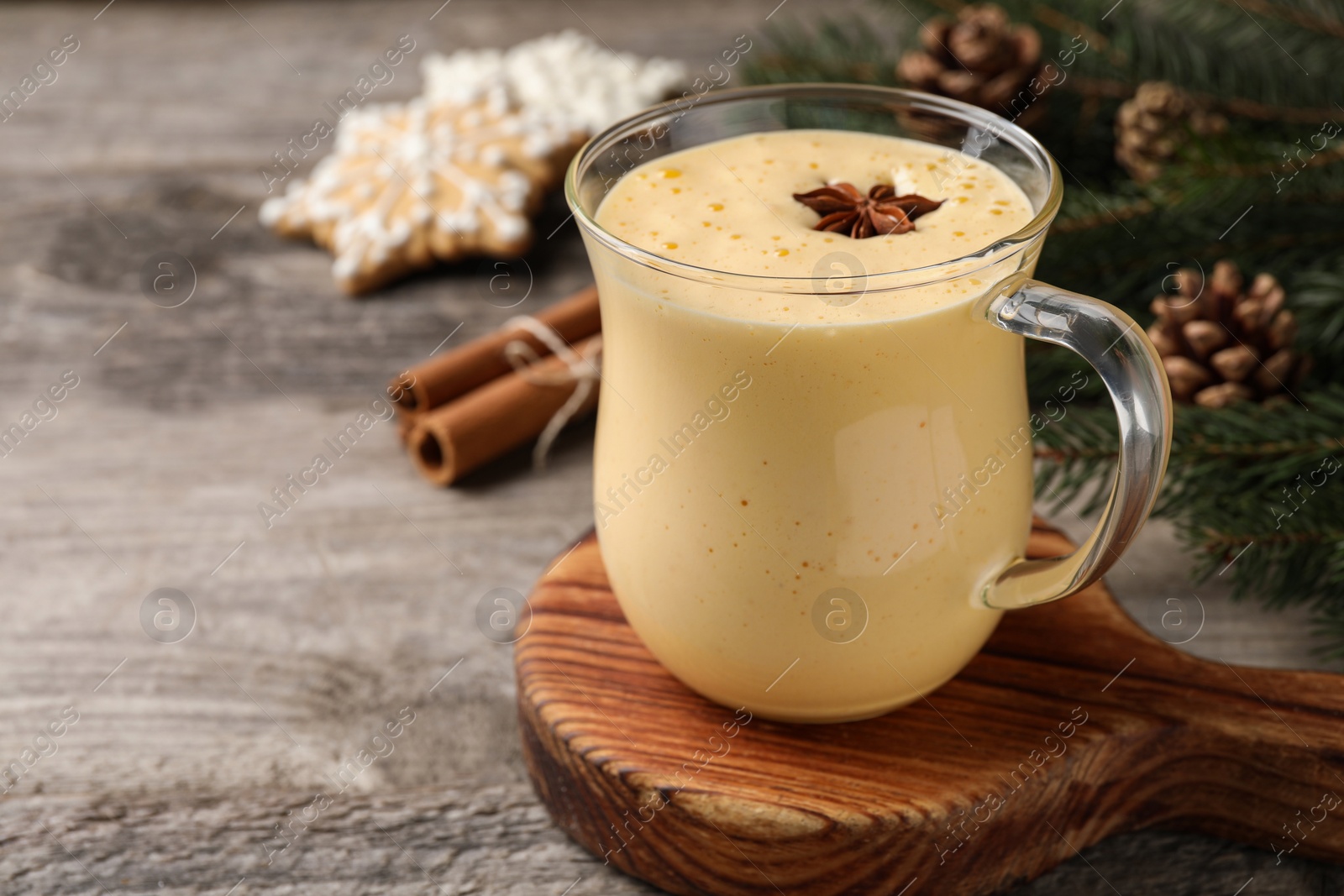 Photo of Glass of delicious eggnog with anise star on wooden table, space for text