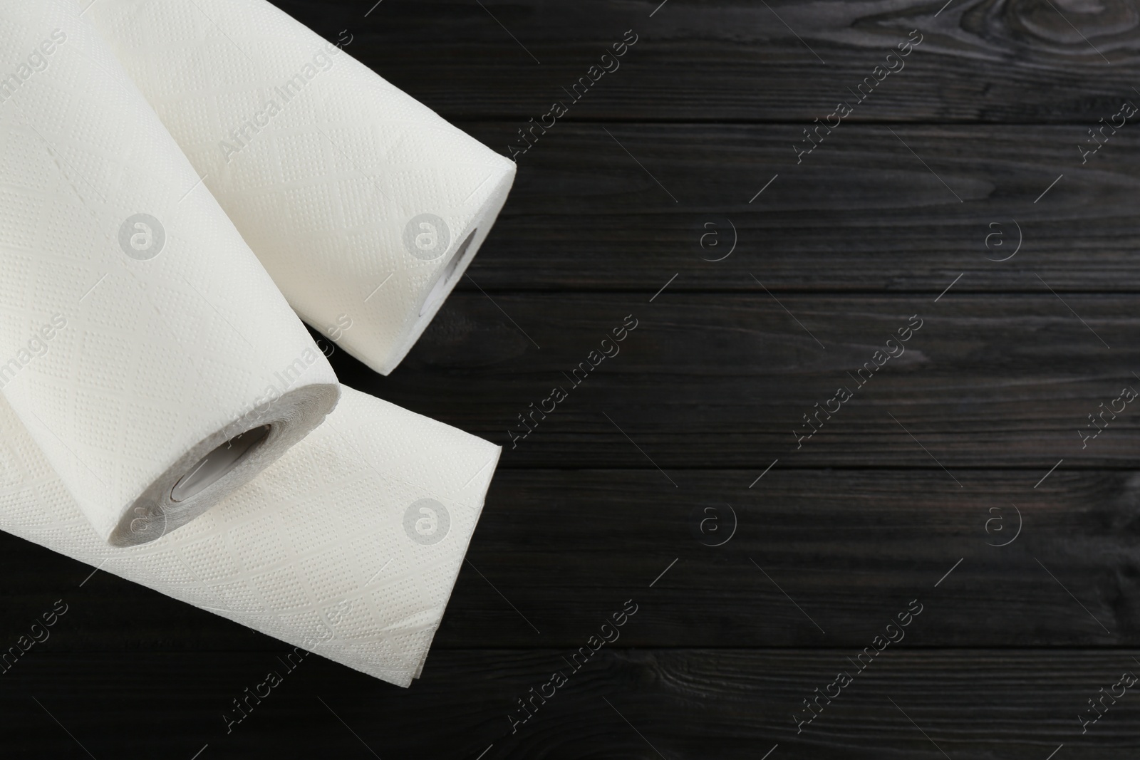 Photo of Rolls of paper towels on wooden table, flat lay. Space for text