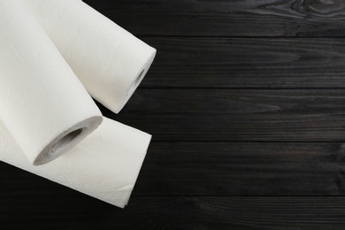 Photo of Rolls of paper towels on wooden table, flat lay. Space for text