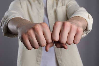 Photo of Man showing fists with space for tattoo on grey background, selective focus
