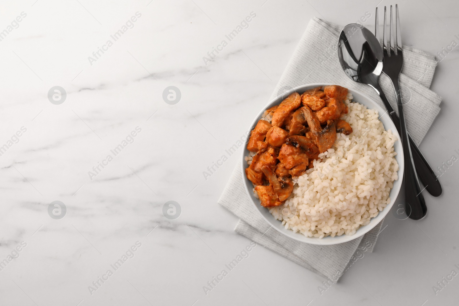 Photo of Bowl of delicious rice with meat and mushrooms served on white marble table, flat lay. Space for text