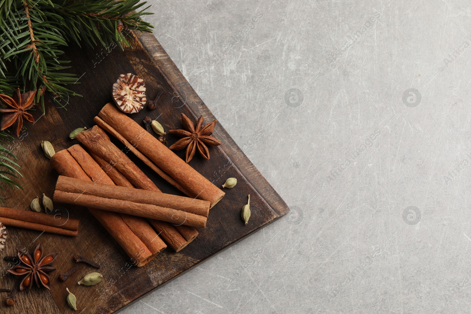 Photo of Board with different aromatic spices and fir branches on light table, top view. Space for text