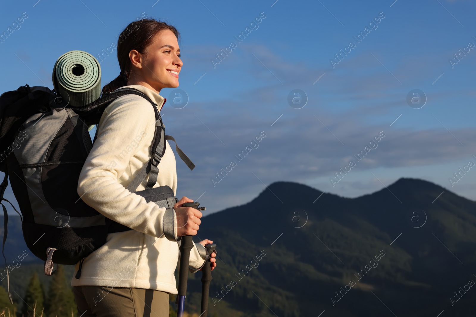 Photo of Tourist with backpack and trekking poles enjoying mountain landscape, space for text