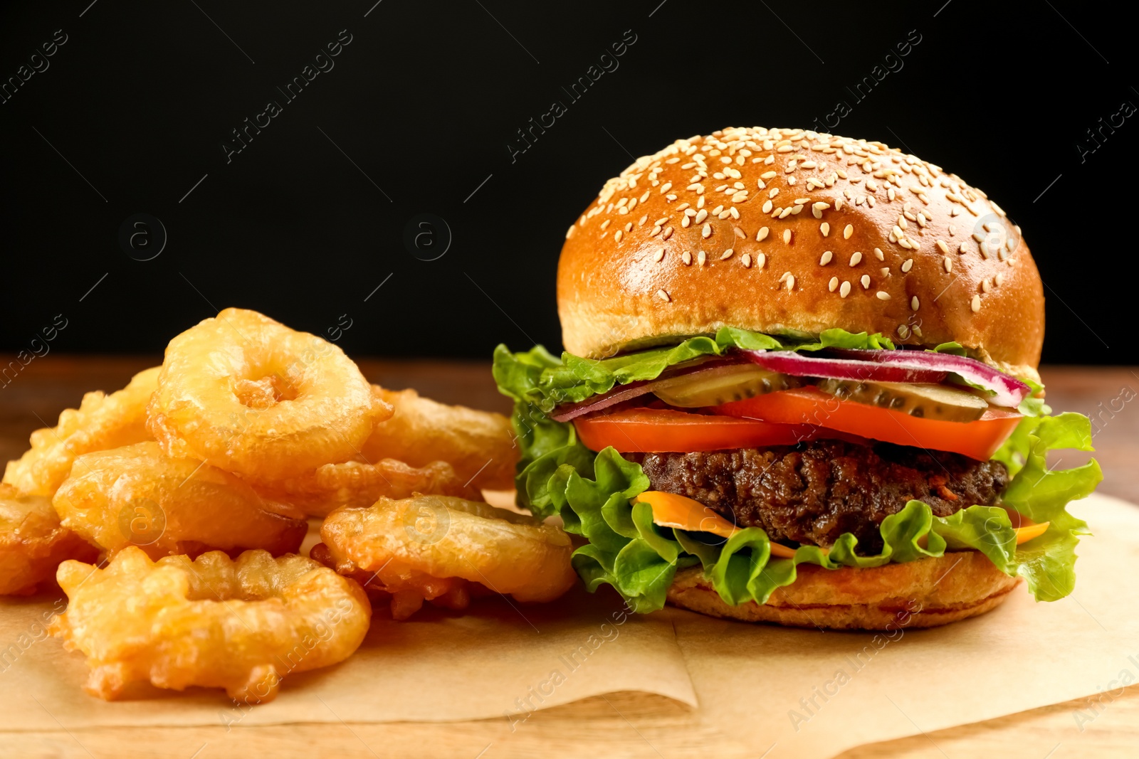 Photo of Burger and fried onion rings on table, closeup. Fast food